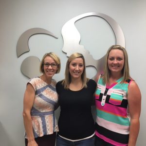 three women smiling in front of the Idaho Fertility Center logo